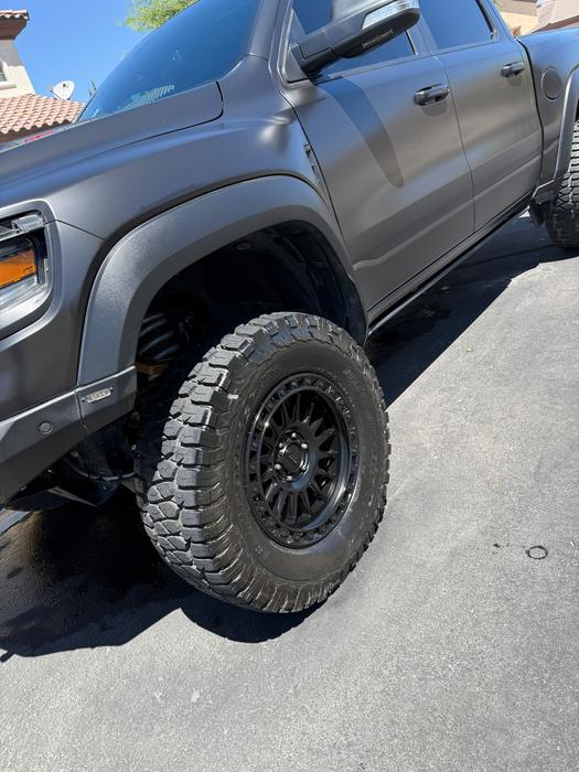 Lifted grey GMC Sierra front wheel and off-road tire cleaned and dressed