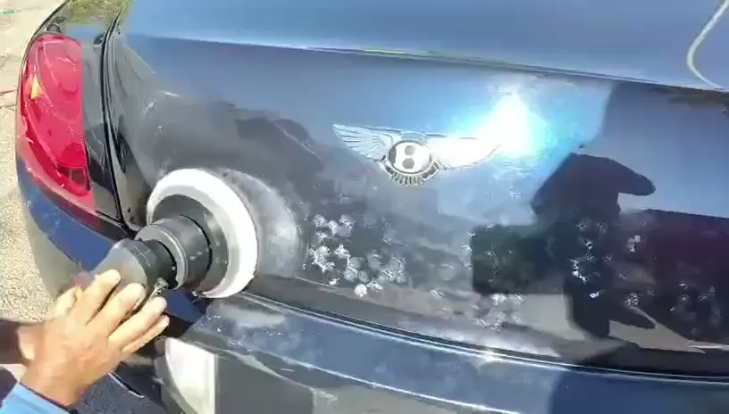 Machine polisher working compound over the rear deck of a Bentley being detailed by Coco Detailers