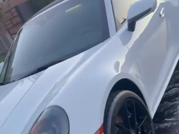 Detailed white Porsche 911 Targa parked in a driveway, whole car in frame